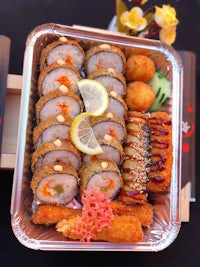 a tray full of sushi and vegetables on a table