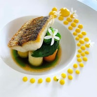 a white plate with a fish and vegetables on it