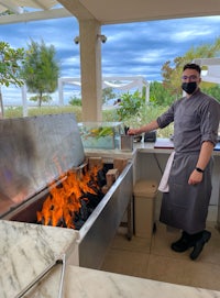 a chef standing in front of a fire pit